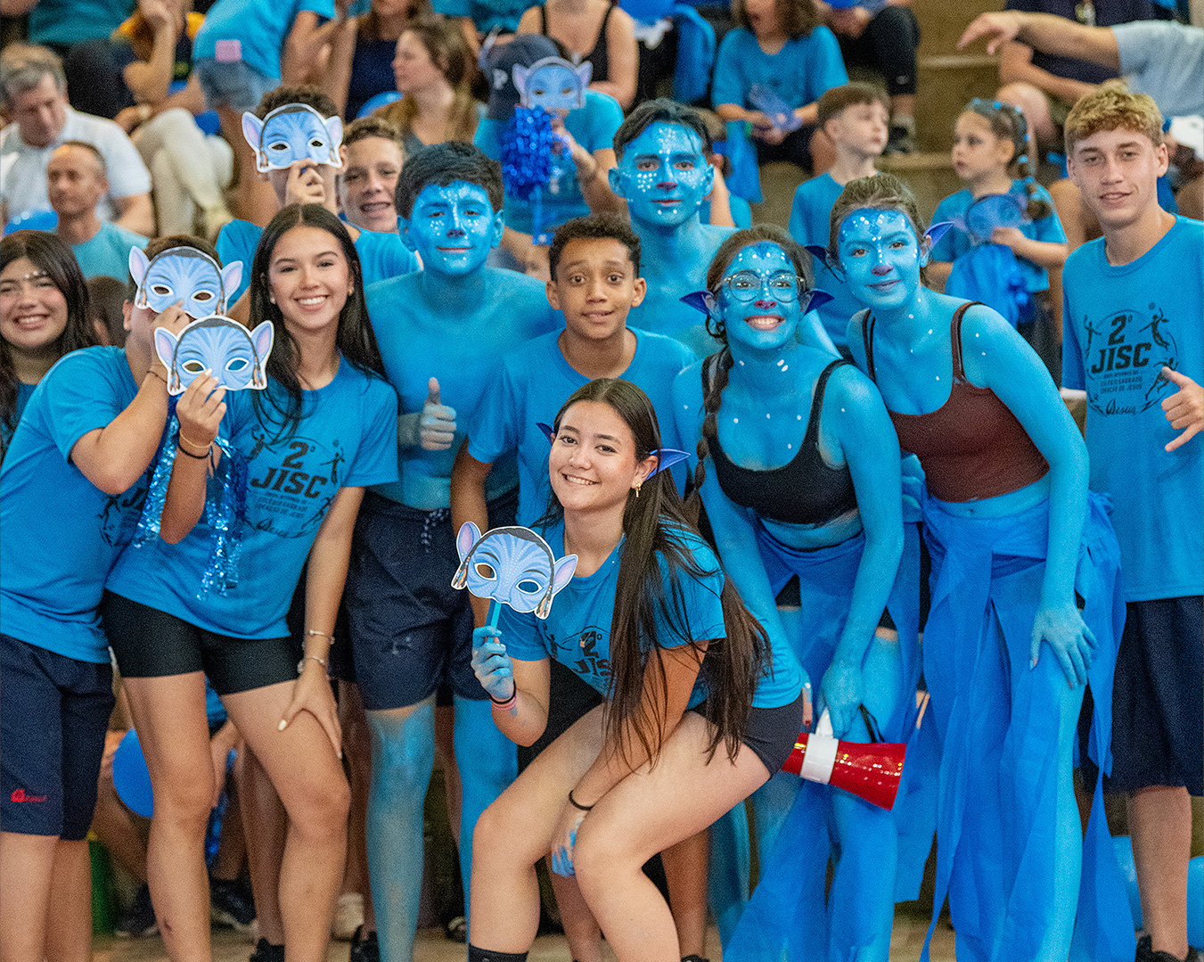 Equipe da gincana reunida de azul, alguns com o rosto e o corpo pintados, posando sorrindo para a foto na arquibancada