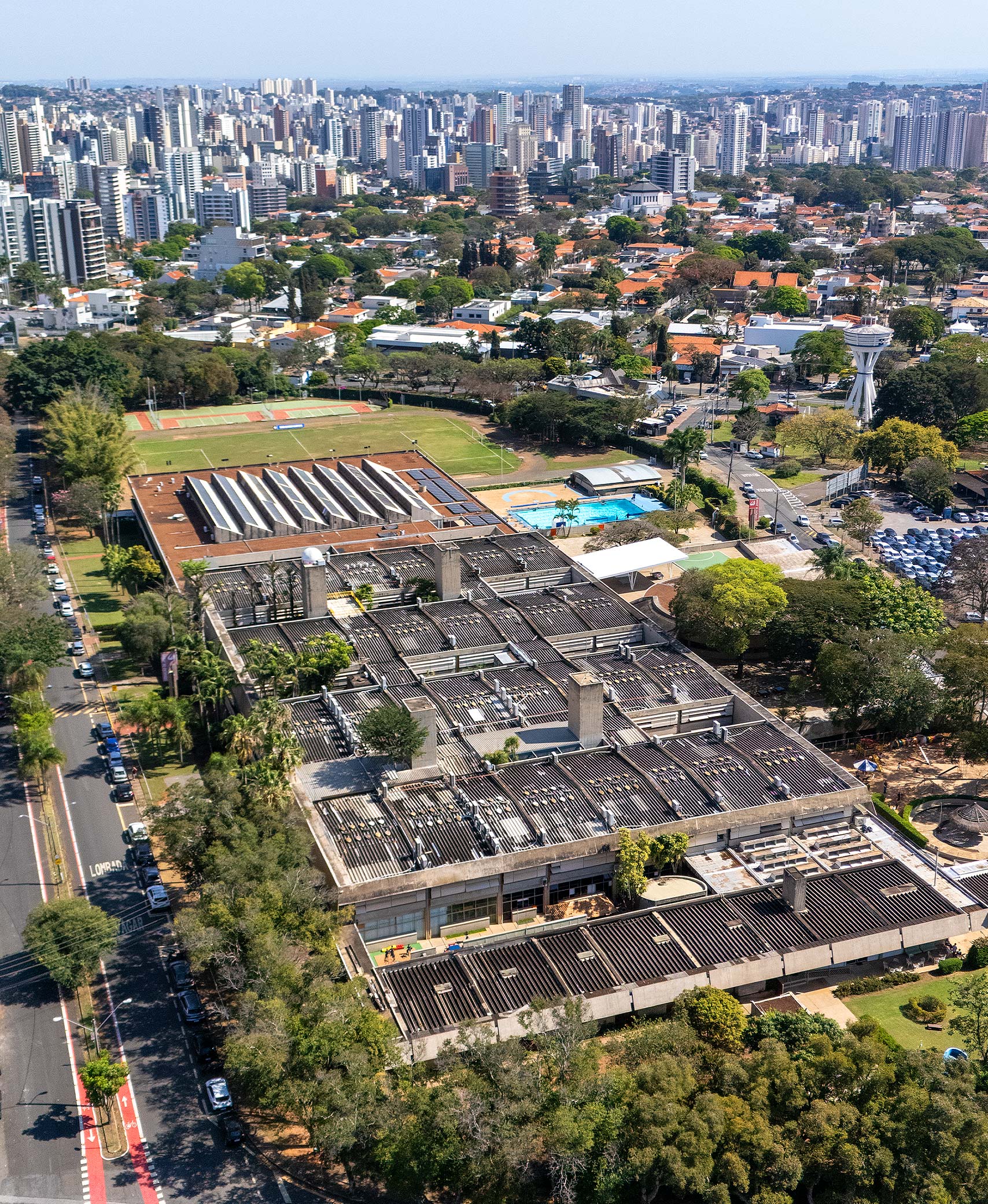 Vista aérea do campus do Colégio Sagrado Coração de Jesus, com os prédios, as quadras e as áreas verdes, e a cidade de Campinas ao fundo